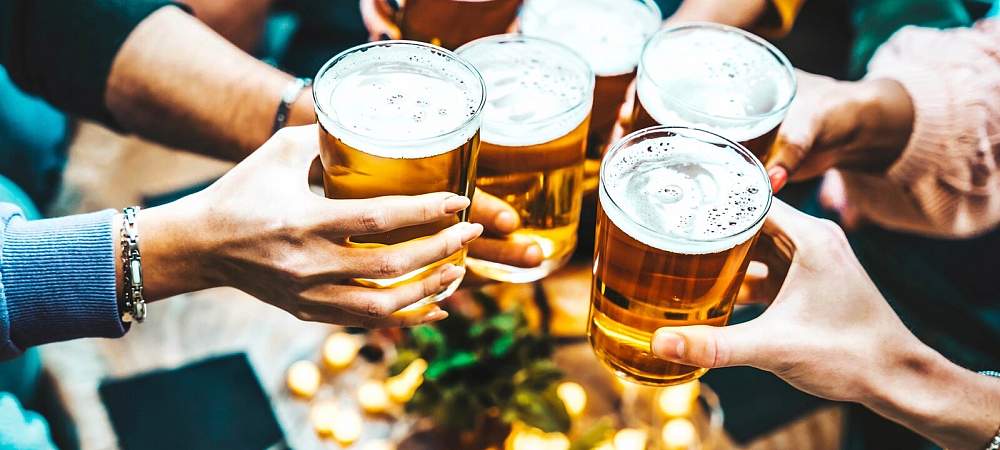 Group of people drinking beer at brewery pub restaurant - Happy friends enjoying happy hour sitting at bar table - Closeup image of brew glasses - Food and beverage lifestyle concept - © Shutterstock