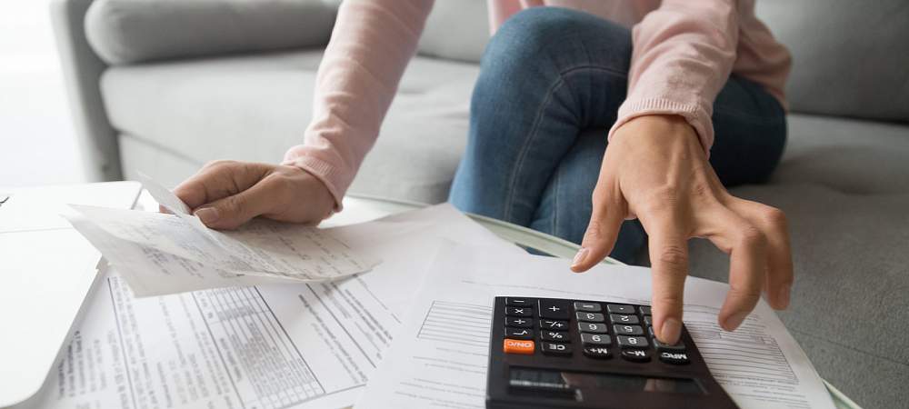 Woman renter holding paper bills using calculator for business financial accounting calculate money bank loan rent payments manage expenses finances taxes doing paperwork concept, close up view - © Shutterstock