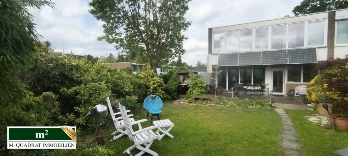 Blick gartenseitig auf Terrasse u. vier Solarmodule
